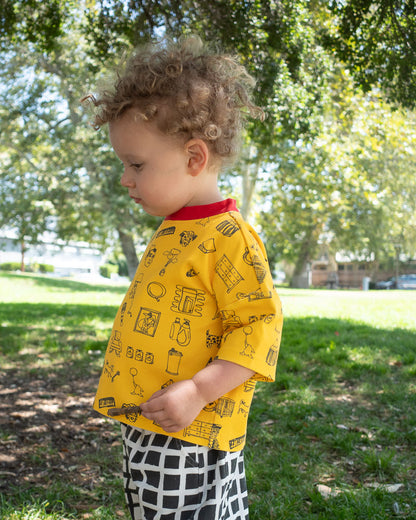 Child wearing a yellow shirt with black doodle patterns in a park
