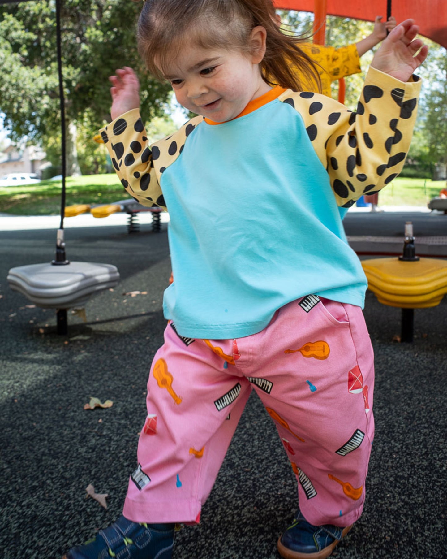 Child in pink printed instrument pants playing on playground equipment