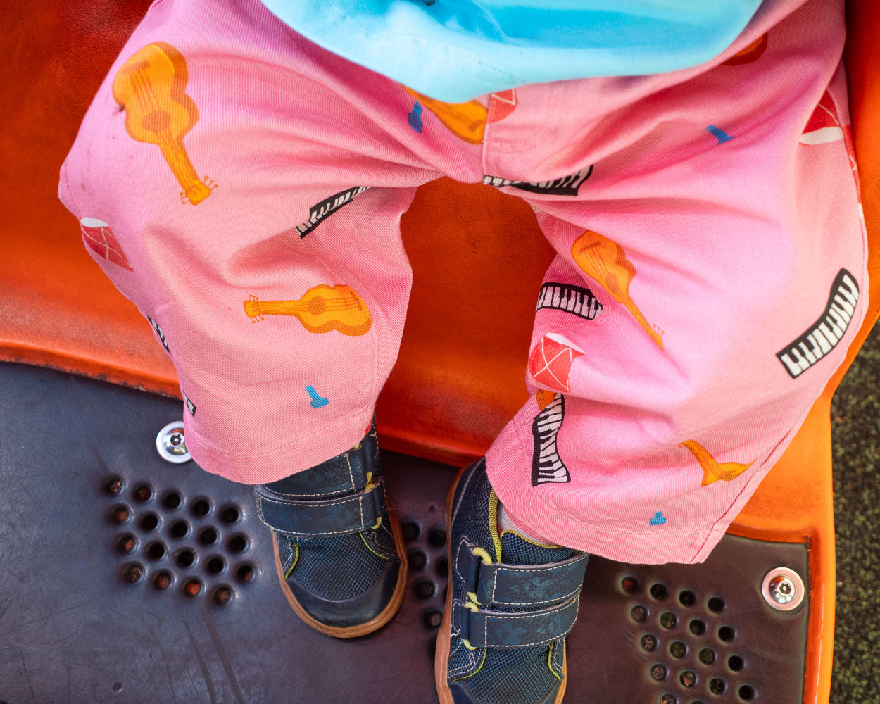 child wearing pink pants with musical instrument patterns on playground.