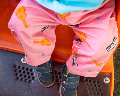 child wearing pink pants with musical instrument patterns on playground.